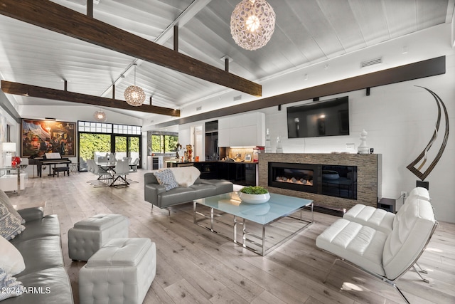 living room with an inviting chandelier, lofted ceiling with beams, and light wood-type flooring