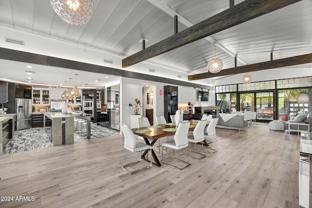 dining space featuring beamed ceiling, an inviting chandelier, light hardwood / wood-style floors, and high vaulted ceiling