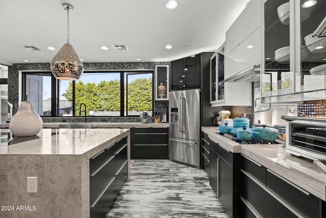 kitchen featuring sink, pendant lighting, high quality fridge, decorative backsplash, and a kitchen island