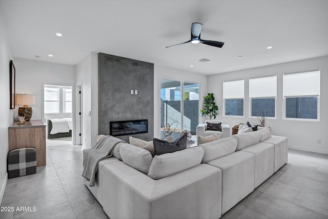 living room with ceiling fan and a large fireplace