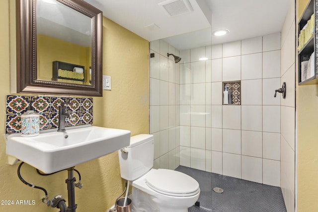 bathroom with a tile shower, decorative backsplash, and toilet