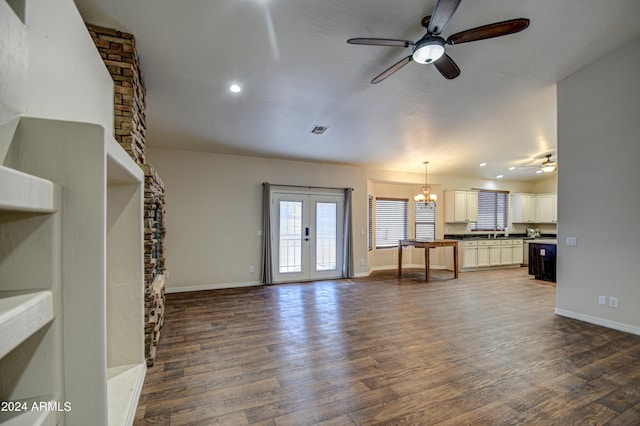 unfurnished living room featuring french doors, ceiling fan with notable chandelier, and dark hardwood / wood-style flooring