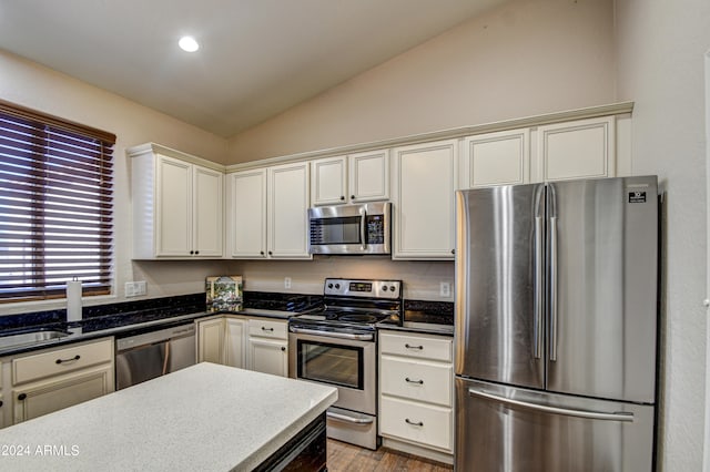 kitchen featuring vaulted ceiling, appliances with stainless steel finishes, and light hardwood / wood-style flooring