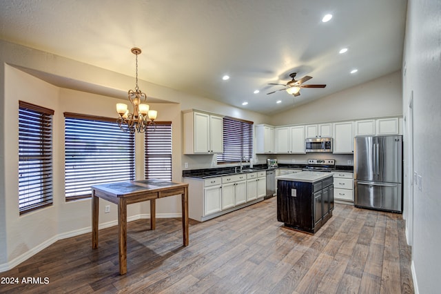 kitchen featuring wood-type flooring, vaulted ceiling, stainless steel appliances, pendant lighting, and a center island