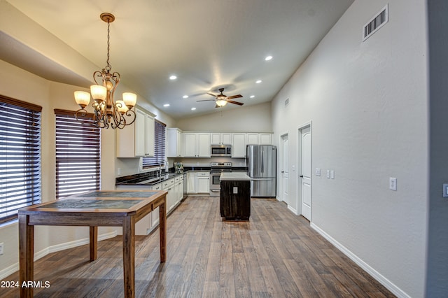 kitchen with white cabinets, hardwood / wood-style flooring, vaulted ceiling, pendant lighting, and stainless steel appliances