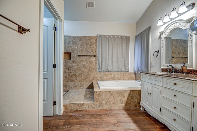 bathroom featuring vanity, a relaxing tiled tub, and hardwood / wood-style floors