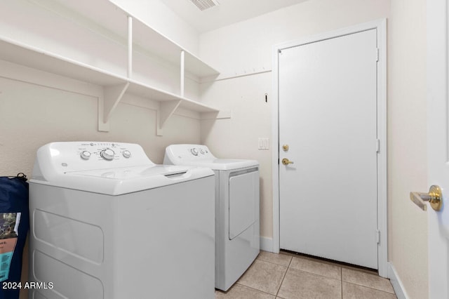 clothes washing area with washer and clothes dryer and light tile floors