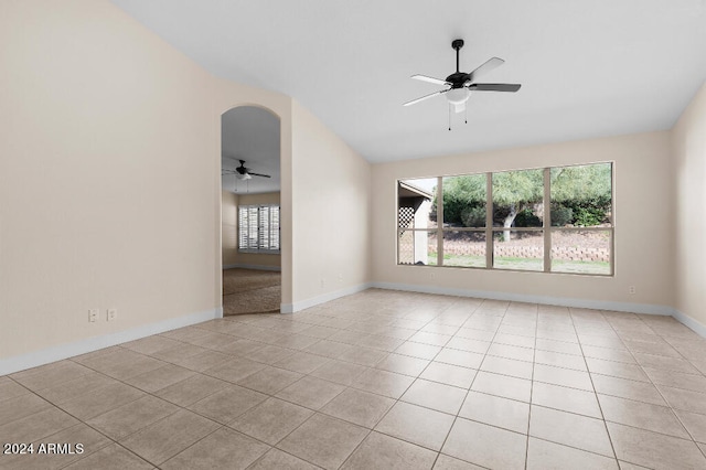 spare room featuring light tile floors, lofted ceiling, and ceiling fan