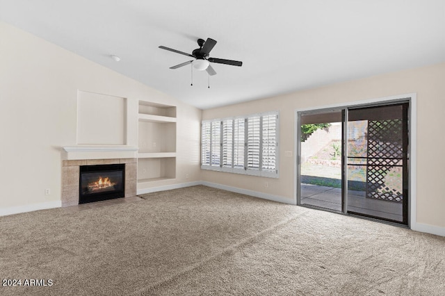 unfurnished living room featuring light colored carpet, ceiling fan, a tile fireplace, built in features, and vaulted ceiling