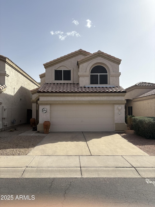 mediterranean / spanish home featuring driveway, an attached garage, a tiled roof, and stucco siding