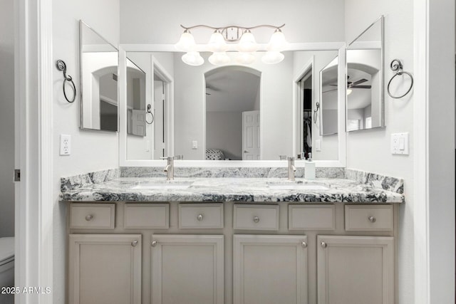 full bathroom featuring double vanity, a sink, toilet, and ceiling fan