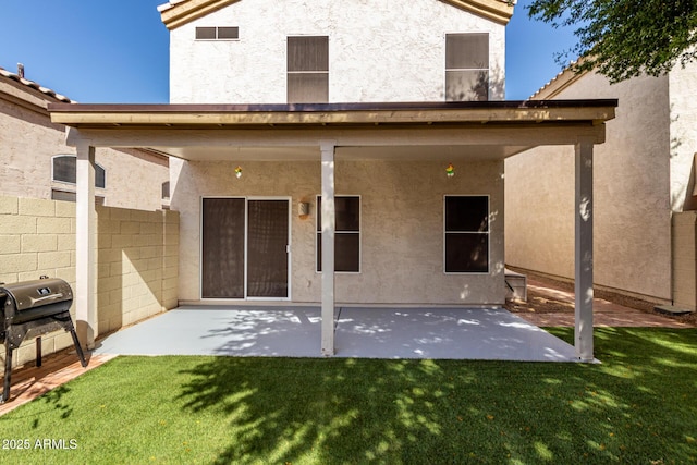 back of property featuring a patio area, a lawn, and stucco siding