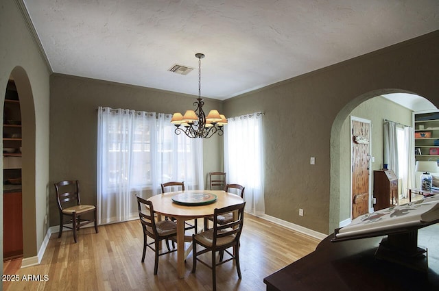 514 W Monte Vista Rd, Phoenix, AZ 85003 - dining room with arched walkways, crown molding, a chandelier, light wood-style floors, and a textured wall