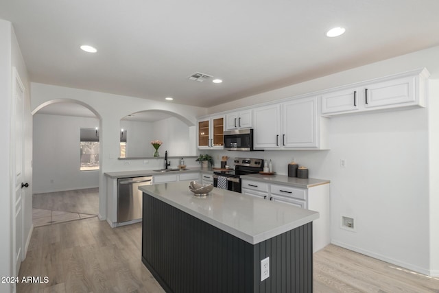 kitchen with stainless steel appliances, light wood-type flooring, white cabinetry, and a kitchen island