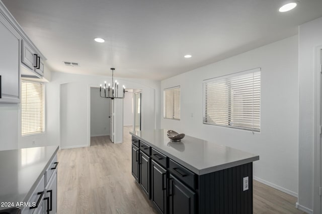 kitchen featuring dark cabinetry, light wood-type flooring, visible vents, and a center island