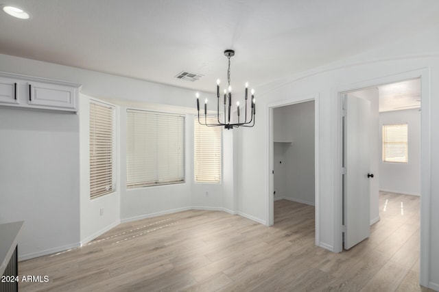 unfurnished dining area featuring a chandelier, light wood finished floors, visible vents, and baseboards