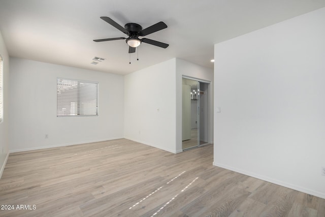 unfurnished room with a ceiling fan, light wood-type flooring, visible vents, and baseboards