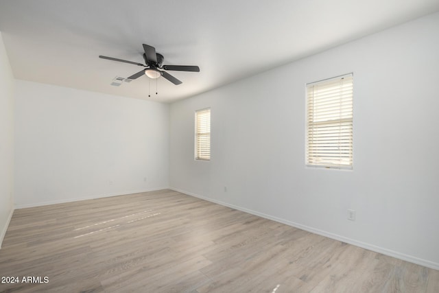 empty room featuring ceiling fan, light wood finished floors, visible vents, and baseboards