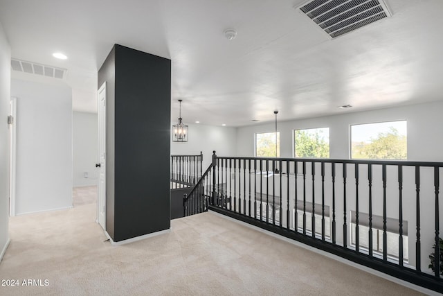 hallway featuring an upstairs landing, visible vents, a notable chandelier, and carpet flooring