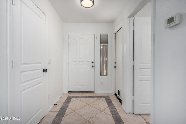 doorway with light tile patterned flooring and baseboards