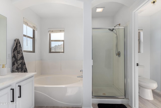 full bathroom with a garden tub, toilet, a stall shower, vanity, and wood finished floors