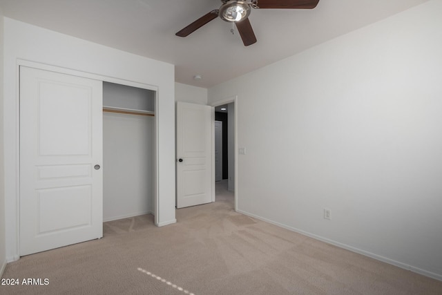 unfurnished bedroom featuring light carpet, ceiling fan, a closet, and baseboards