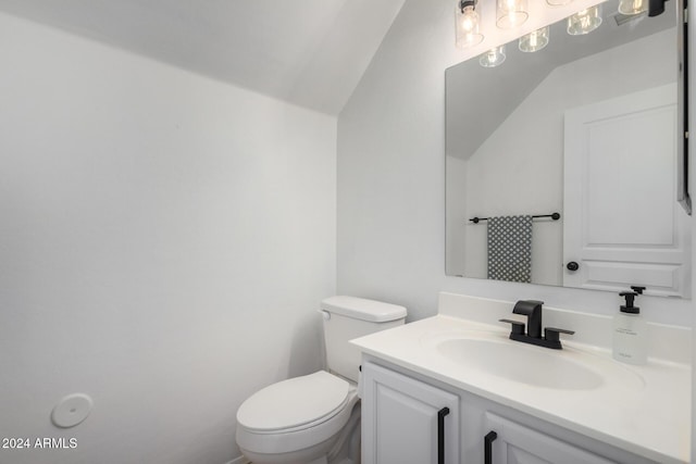 half bathroom featuring vaulted ceiling, vanity, and toilet