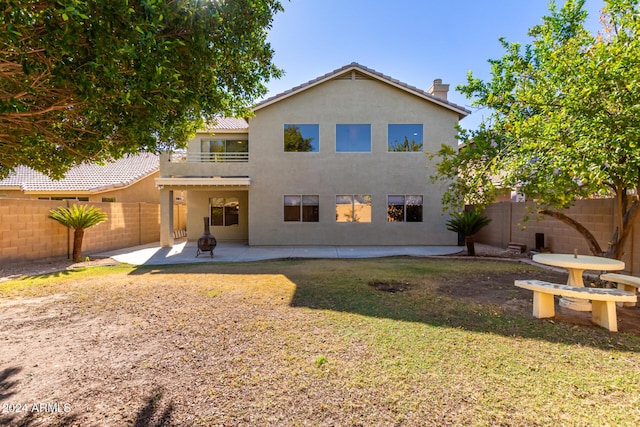 rear view of property featuring a patio, a balcony, a fenced backyard, a yard, and stucco siding