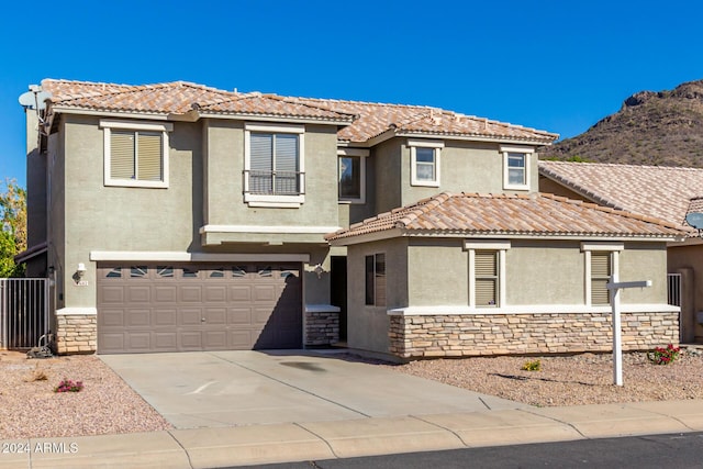 view of front of property with stone siding, a tiled roof, concrete driveway, and stucco siding