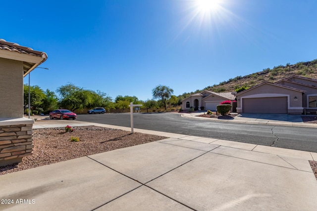 view of street with street lighting, concrete driveway, and sidewalks