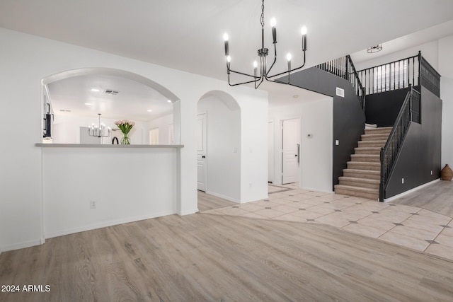 entryway with stairway, visible vents, a chandelier, and wood finished floors