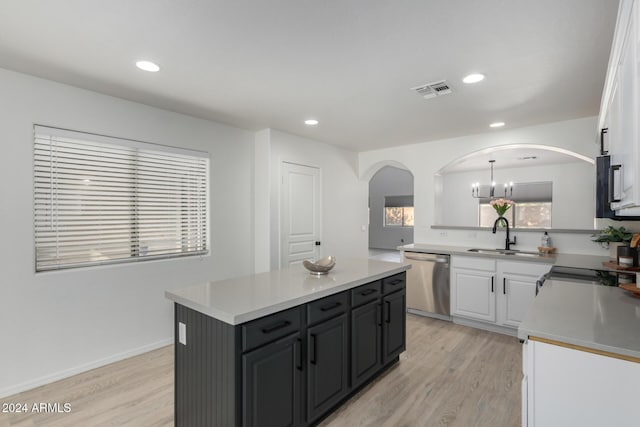 kitchen with arched walkways, white cabinets, light wood-style flooring, light countertops, and stainless steel dishwasher