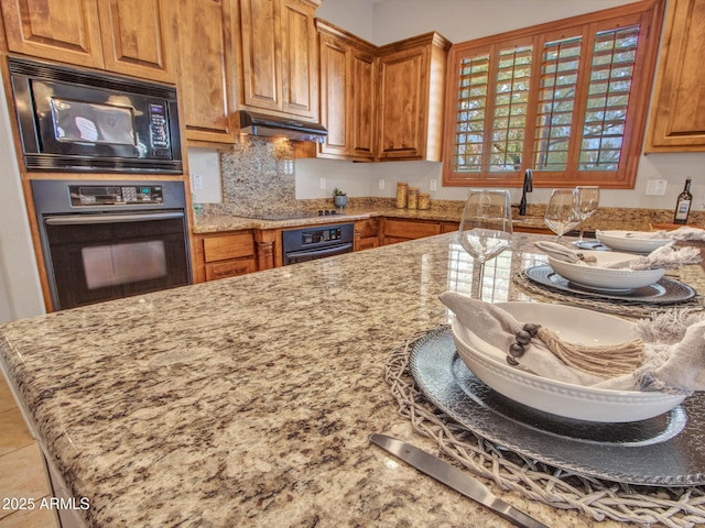2724 W Fernwood Dr, Phoenix, AZ 85086 - kitchen with light stone countertops, under cabinet range hood, black appliances, and brown cabinetry