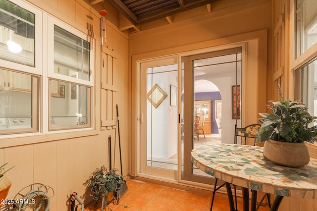 doorway with wooden walls and light tile patterned floors