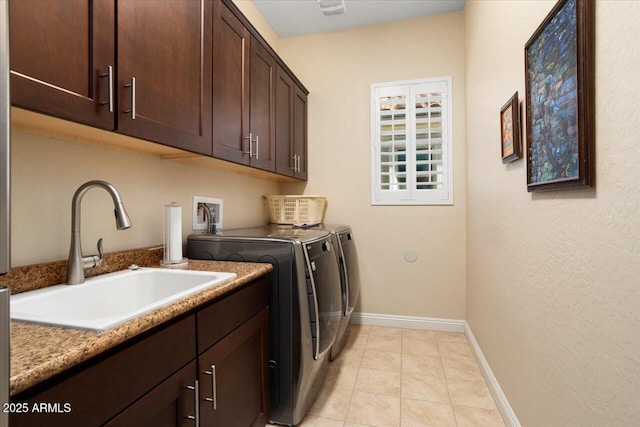 clothes washing area featuring sink, light tile patterned flooring, cabinets, and washer and dryer