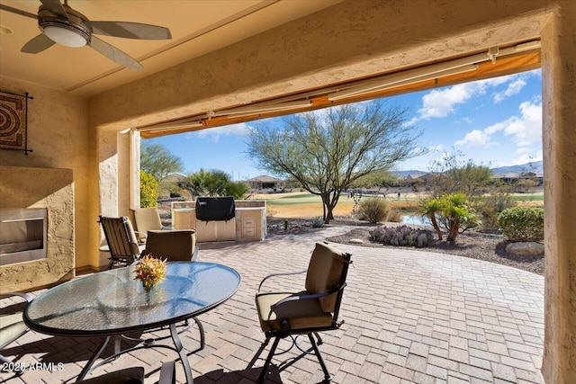 view of patio / terrace featuring exterior kitchen, a mountain view, and ceiling fan