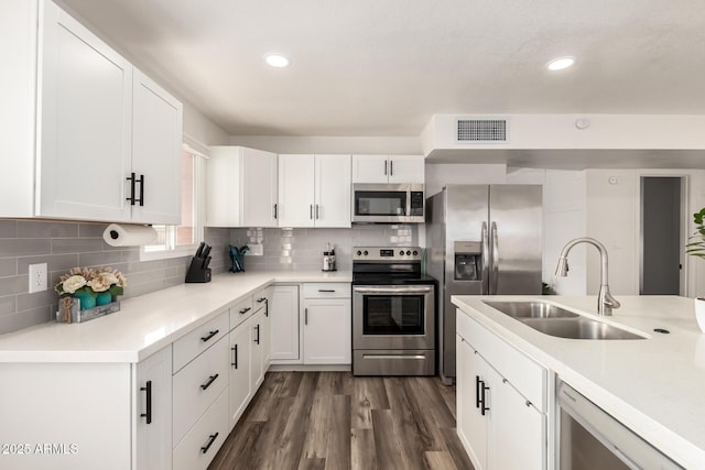 kitchen featuring visible vents, backsplash, appliances with stainless steel finishes, dark wood-style floors, and a sink