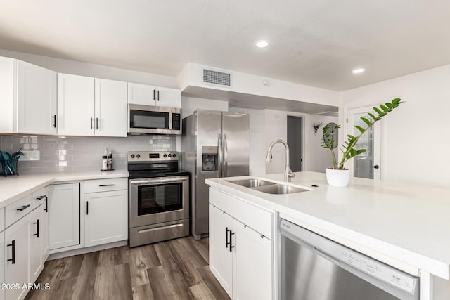 kitchen with visible vents, a sink, backsplash, white cabinetry, and appliances with stainless steel finishes