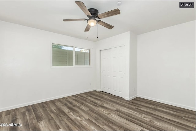 empty room with dark wood finished floors, a ceiling fan, and baseboards