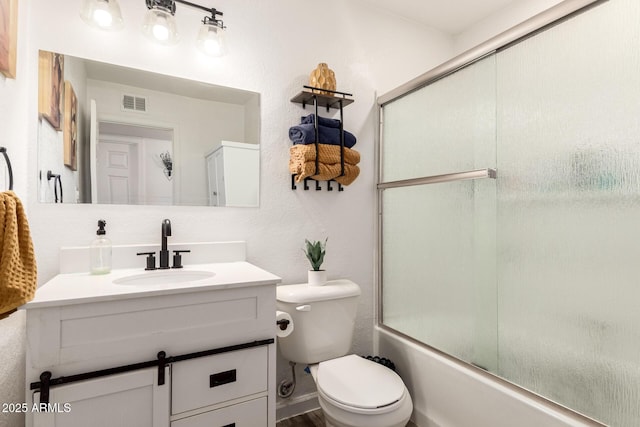 full bath featuring visible vents, toilet, a textured wall, shower / bath combination with glass door, and vanity