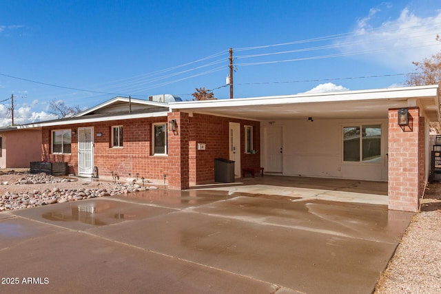 ranch-style home with an attached carport, brick siding, and driveway