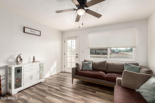 living area featuring baseboards, wood finished floors, and a ceiling fan