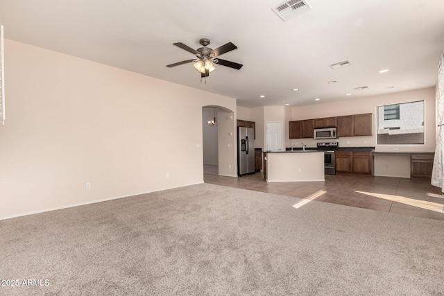 kitchen with sink, light carpet, a center island with sink, appliances with stainless steel finishes, and ceiling fan