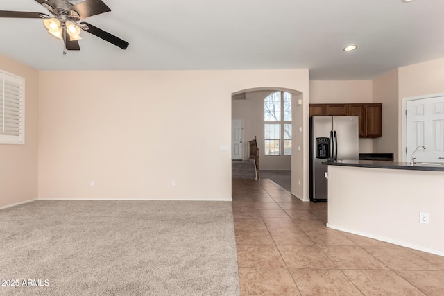 kitchen featuring sink, dark brown cabinets, light carpet, stainless steel fridge, and ceiling fan