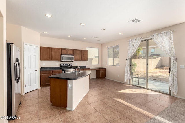 kitchen with stainless steel appliances, sink, a kitchen island with sink, and a wealth of natural light