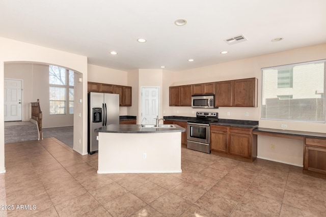 kitchen with stainless steel appliances, sink, and a center island with sink