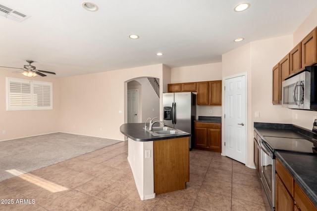 kitchen with sink, light carpet, an island with sink, ceiling fan, and stainless steel appliances