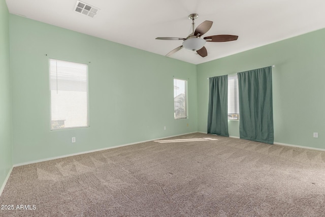 empty room with ceiling fan, plenty of natural light, and carpet