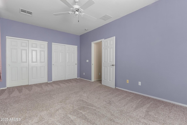 unfurnished bedroom with carpet, two closets, and ceiling fan