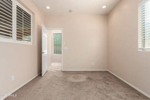 spare room featuring light carpet and a wealth of natural light